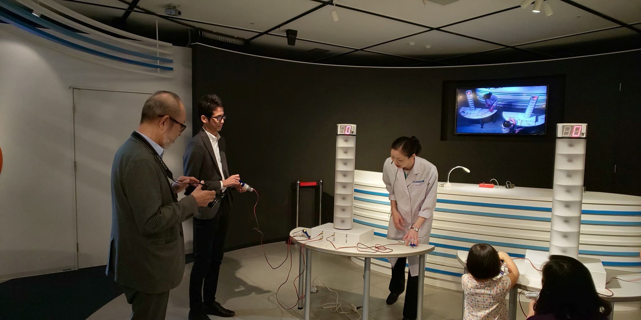 写真)小型発電機を手動で回して電気を起こしタワーの電球を点灯させる実験